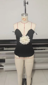 Détail d'un corset bustier noir orné d'une grande fleur 3D en satin blanc contrastant