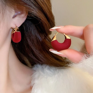 Detailed view of red flocked bow earrings with pearls and crystals on a female model