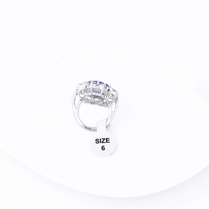 Detail of sapphire engagement ring with halo diamonds and size 6 tag on white tray