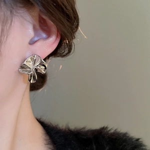 Close-up of minimalist silver irregular pleated flower earring on a model ear