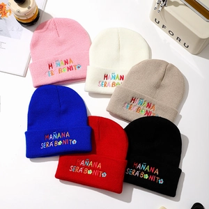 Flat lay of colorful knit beanies with Mañana Sera Bonito floral embroidery in six colors