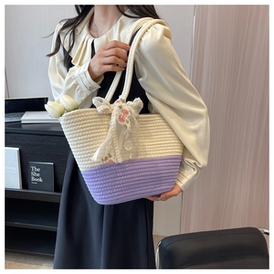 Close-up of a woven tote bag featuring a purple and beige two-tone design with floral lace ribbon