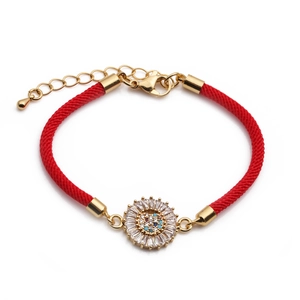 Detailed view of red braided bracelet with golden sunflower pendant and zircon stones