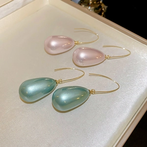 Dettaglio di orecchini a goccia di perle rosa e color foglia di tè in scatola di raso