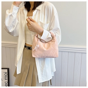 Pink glossy faux leather dumpling bag detail with pleated texture and beaded charm decor