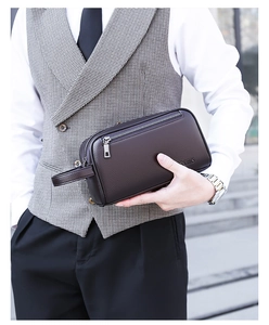 Detail view of coffee brown leather clutch bag with litchi grain and side handle strap