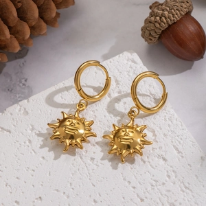 Vintage 18K gold plated stainless steel sun face drop earrings on a stone background