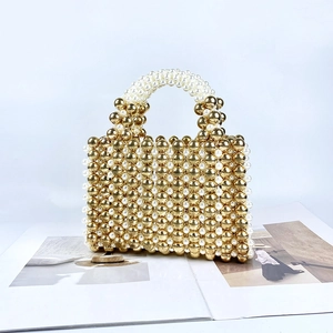 Close-up of handmade gold and white pearl beads weaving texture on evening bag