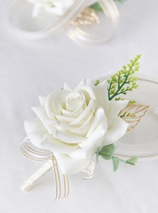 Close-up of cream satin rose boutonniere with golden metal leaves for wedding decor