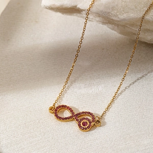 Macro shot of gold infinity necklace pendant with sparkling purple rhinestones
