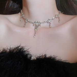 Detail shot of silver necklace featuring rhinestone teardrop and delicate pendant elements
