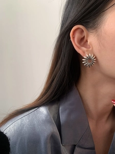 Macro detail of a vintage silver hollow flower earring worn by a model in soft lighting