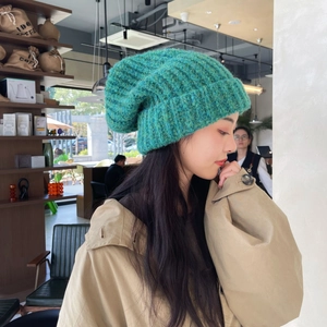 Detail of teal chunky knit beanie on model showing thick texture and slouchy fit
