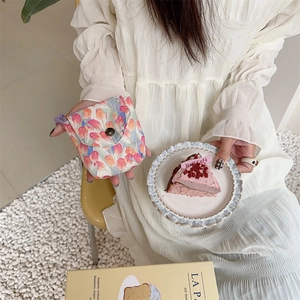 Mini floral pouch with tulip pattern and metal button closure held in a lifestyle setting