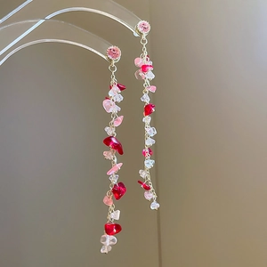 Detail of pink stone fringe earrings with gold chains on a clear display stand