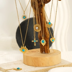 Detailed close-up of gold bohemian necklaces with turquoise pendants on a wood stand