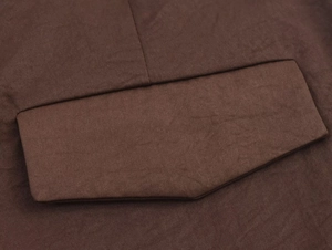 Close-up of the pocket flap detail on a dark brown textured fabric vest and trousers