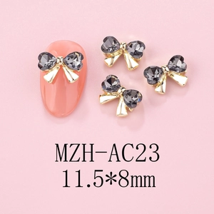 Detail of 3D bow nail art charms with golden alloy base and grey heart rhinestones