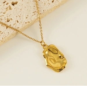 Close-up of golden irregular wrinkled pendant with flowing metallic texture on cross chain