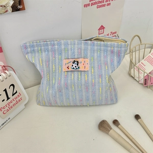 Détail d'une trousse de maquillage en tricot rayé bleu avec un écusson chiot mignon