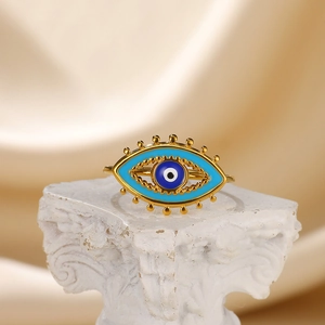 Macro shot of gold stainless steel evil eye ring with blue enamel on a white pillar