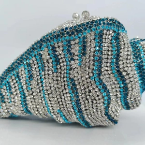 Detail of shell-shaped clutch bag featuring blue and silver rhinestone stripes and metal clasp