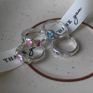 Set of 4 silver open rings featuring heart and colorful zircon stones on ceramic plate