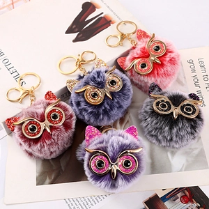 Macro detail of multi-color plush owl keychains with rhinestone eyes on a fashion magazine