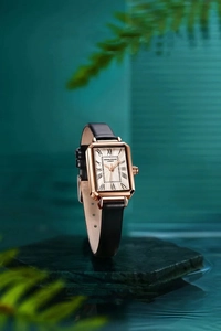 Detail of a vintage-style women's square watch in rose gold with a black leather strap.