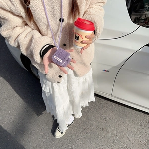 Close-up of purple plush earphone pouch with crossbody strap on lamb wool coat