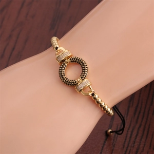 Detail of adjustable black cord bracelet with gold ring pendant and cubic zirconia