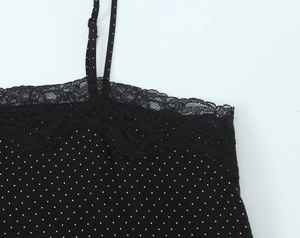 Detailed close-up of black polka dot top featuring delicate lace trim and thin straps