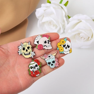 Set aus fünf Punk-Gothic-Emaille-Pins mit Totenkopf- und Blumenmotiven auf der Hand