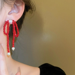 Detail of red crystal beaded bow earrings with white pearl drop on female model