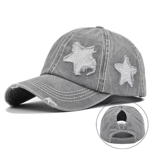 Detail of washed grey ponytail baseball cap featuring silver sequin stars and frayed edges