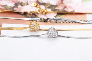 Close-up of gold and silver heart pendants with micro-pave cubic zirconia on snake chain