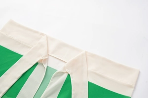 Detail of the green and beige ruffled neckline with adjustable ties on a swimsuit