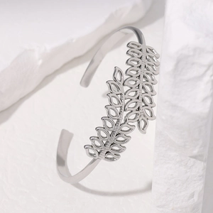 Minimalist silver stainless steel open bangle with hollow leaf pattern on stone background
