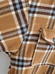 Gros plan d'un manteau en laine à carreaux marron et bleu avec poche à rabat