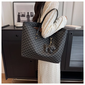 Detail of the large monogram tote bag with leather straps and elephant charm accessory