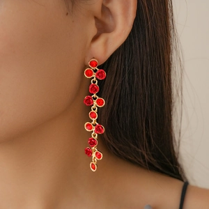 Gros plan de boucles d'oreilles dorées avec motifs floraux rouges et pierres précieuses