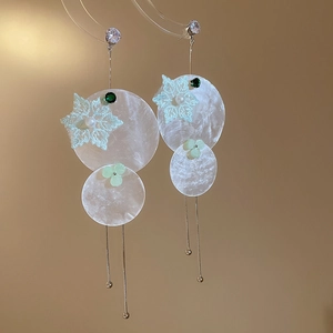 Detail of silver drop earrings featuring lace flowers, pearls, and round shell discs