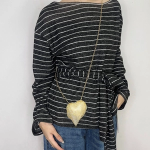 Detailed close-up of a heart-shaped golden rhinestone mini bag worn over a striped top