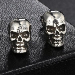 Macro shot of silver hip-hop skull stud earrings with vintage metal texture on leather