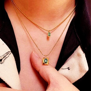 Double layered gold bead necklaces with emerald green zircon pendant on model neck