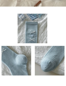Close-up of light blue knit socks featuring white bows and transparent flower details