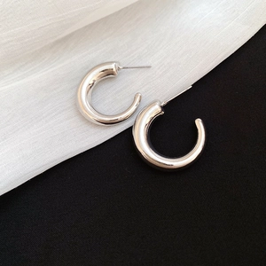 Polished silver C-shaped hoop earrings displayed on a high-contrast minimalist background