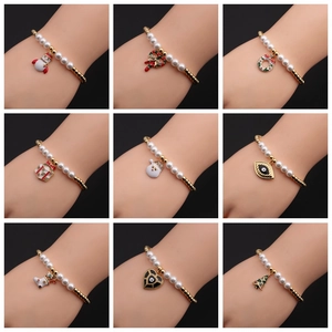 Detail view of gold-plated beaded bracelets featuring Christmas and evil eye charms on wrist