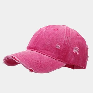 Dettaglio a 45 gradi di un berretto da baseball fucsia slavato con bordi consumati