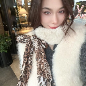 Detail of white faux fur scarf with leopard print ribbon bow in a stylish winter look